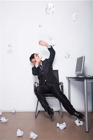 failure - Young Businessman protecting himself from being hit by crumpled up pieces of paper Stock Photo - Premium Royalty-Free, Code: 6116-07086736