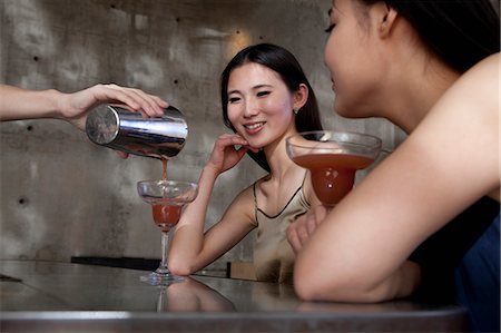 Young women having cocktails, sitting at the bar counter Foto de stock - Sin royalties Premium, Código: 6116-07235662