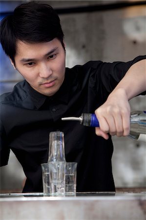 Bartender pouring licour on shot glass pyramid Photographie de stock - Premium Libres de Droits, Code: 6116-07235667