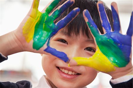 Portrait of smiling schoolboy finger painting, close up on hands Stock Photo - Premium Royalty-Free, Code: 6116-07235679