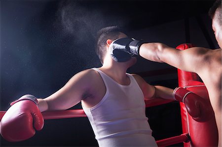 punching - Over the shoulder view of male boxer throwing a knockout punch in the boxing ring Photographie de stock - Premium Libres de Droits, Code: 6116-07235779