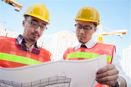 Two architects looking at a blueprint outdoors at a construction site Photographie de stock - Premium Libres de Droits, Code: 6116-07235736