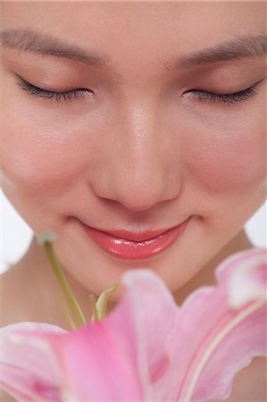 simsearch:614-01869829,k - Close -Up of young beautiful woman smelling a  large pink flower, studio shot Stock Photo - Premium Royalty-Free, Code: 6116-07235842