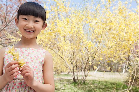 Portrait of smiling girl holding a yellow flower in the park in springtime Photographie de stock - Premium Libres de Droits, Code: 6116-07235869