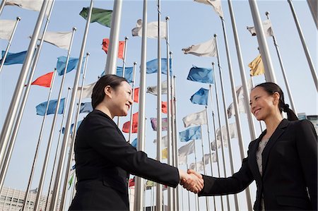 fahnenmast - Two businesswomen shaking hands with flags in background. Photographie de stock - Premium Libres de Droits, Code: 6116-07235822