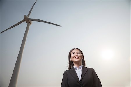 suit man asian - Portrait of smiling young businesswoman standing by a wind turbine Foto de stock - Sin royalties Premium, Código: 6116-07235978