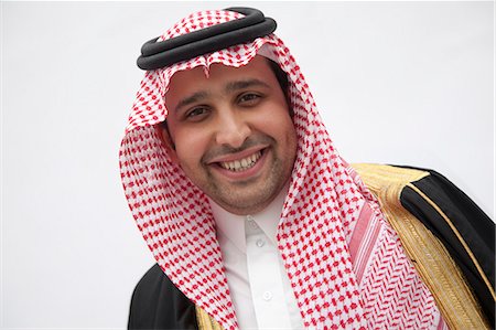 saudi arabia people - Portrait of smiling young man in traditional Arab clothing and Kaffiyeh, studio shot Foto de stock - Sin royalties Premium, Código: 6116-07235996