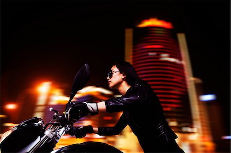 simsearch:6116-07235912,k - Beautiful young woman riding motorcycle in sunglasses through the city streets at night Photographie de stock - Premium Libres de Droits, Code: 6116-07235911