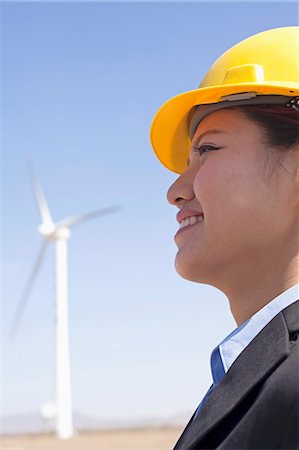 suit man asian - Portrait of young smiling female engineer checking wind turbines on site, side view Foto de stock - Sin royalties Premium, Código: 6116-07235938