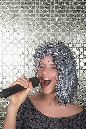 funny wig woman - Young woman in a silver wig holding microphone and singing Stock Photo - Premium Royalty-Free, Code: 6116-07236057