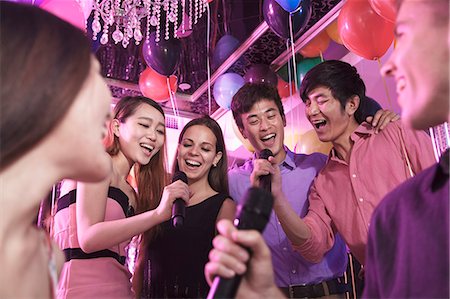 Group of friends holding microphones in a nightclub and singing together karaoke Photographie de stock - Premium Libres de Droits, Code: 6116-07236066