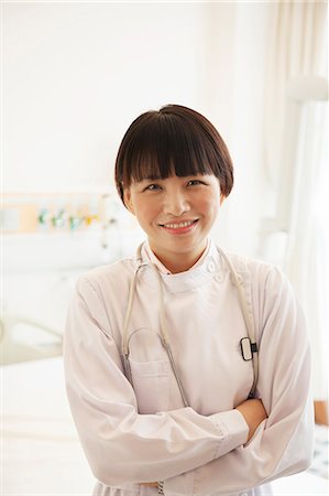 professional occupation - Portrait of smiling young female doctor with arms crossed in a hospital Stock Photo - Premium Royalty-Free, Code: 6116-07236086