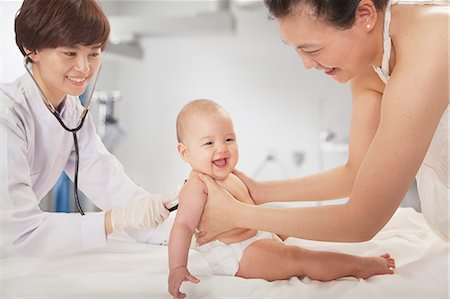 simsearch:6116-07086643,k - Doctor examining the baby with a stethoscope in the doctors office, mother holding the baby Stock Photo - Premium Royalty-Free, Code: 6116-07236016