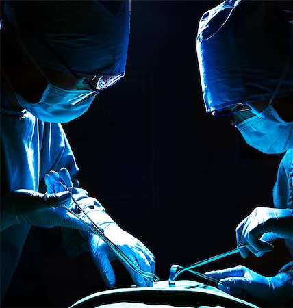 eyeglasses - Two surgeons looking down, working, and holding surgical equipment with patient lying on the operating table Stock Photo - Premium Royalty-Free, Code: 6116-07236158
