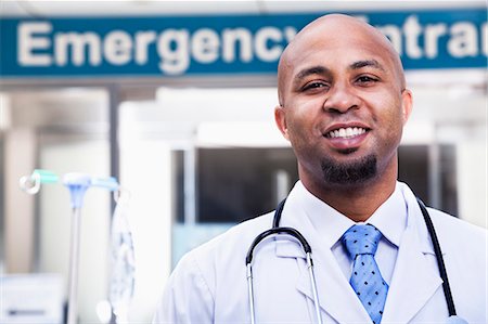 simsearch:6116-07236099,k - Portrait of smiling doctor outside of the hospital, emergency room sign in the background Stock Photo - Premium Royalty-Free, Code: 6116-07236168