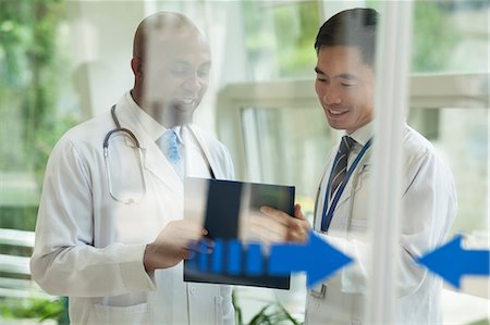 simsearch:6116-07236099,k - Two doctors consulting over medical record on the other side of glass doors Photographie de stock - Premium Libres de Droits, Code: 6116-07236177