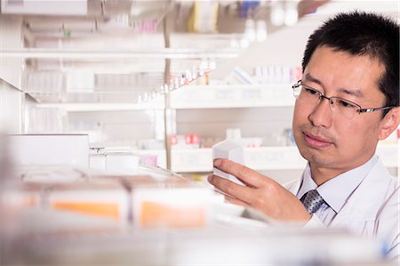 pharmacy shelf - Pharmacist taking down and examining prescription medication in a pharmacy Photographie de stock - Premium Libres de Droits, Code: 6116-07236103