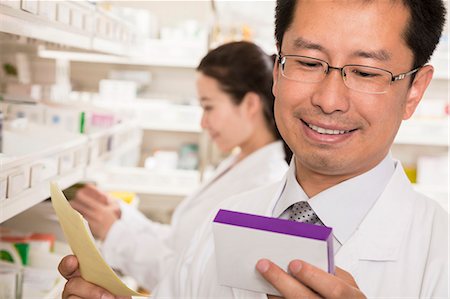 simsearch:649-07804645,k - Pharmacist looking down and examining prescription medication in a pharmacy Photographie de stock - Premium Libres de Droits, Code: 6116-07236107