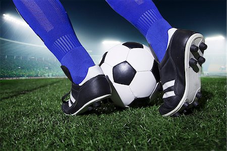 sports close up - Close up of feet kicking the soccer ball, night time in the stadium Stock Photo - Premium Royalty-Free, Code: 6116-07236138