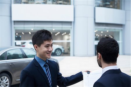 Car salesman holding car keys and paperwork and selling a car to a young businessman Foto de stock - Sin royalties Premium, Código: 6116-07236285