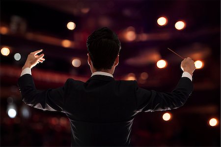 suit man standing backside - Young conductor with baton raised at a performance, rear view Foto de stock - Sin royalties Premium, Código: 6116-07236209