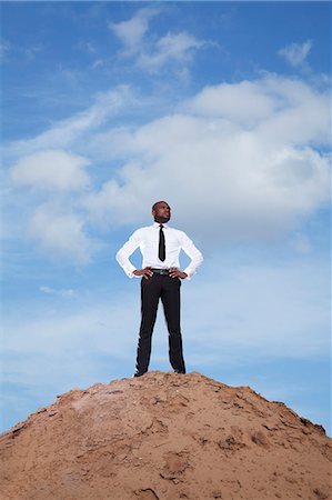 Young businessman with hands on hips in the desert Stock Photo - Premium Royalty-Free, Code: 6116-07236211