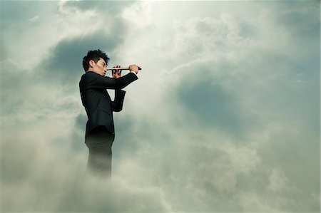 Young businessman looking through telescope in a dreamlike cloud Stock Photo - Premium Royalty-Free, Code: 6116-07236212