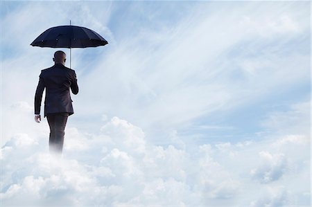 surreal - Businessman holding an umbrella and walking  away in dreamlike clouds Stock Photo - Premium Royalty-Free, Code: 6116-07236216