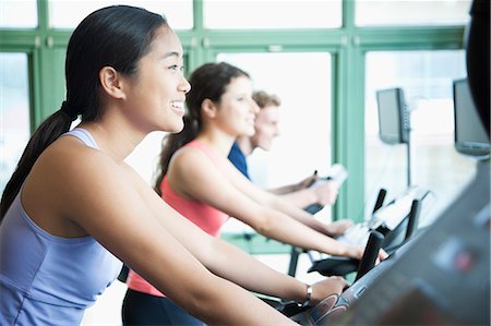 exercise indoors smile asian - Young women exercising on fitness bikes in the gym Stock Photo - Premium Royalty-Free, Code: 6116-07236344