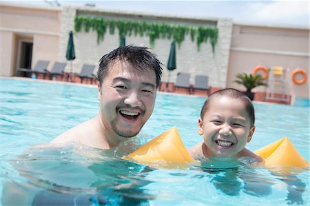 father and son swimming - Portrait of smiling father and son in the pool on vacation Stock Photo - Premium Royalty-Free, Code: 6116-07236392