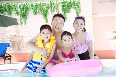 family playing outdoors parent ethnic not beach not park - Family portrait, mother, father, daughter, and son, smiling by the pool Stock Photo - Premium Royalty-Free, Code: 6116-07236313