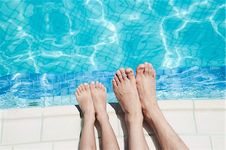 Close up of two people's legs by the pool side Photographie de stock - Premium Libres de Droits, Code: 6116-07236315