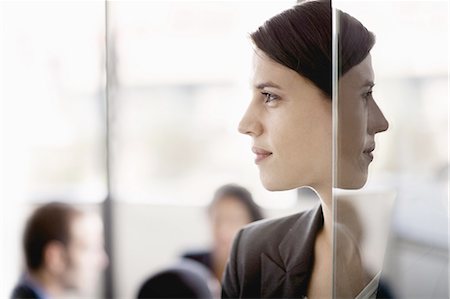 suit (woman's) - Side profile on a businesswoman with coworkers in the background Stock Photo - Premium Royalty-Free, Code: 6116-07236441