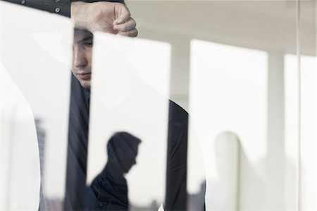 simsearch:693-07456224,k - Overworked businessman with arm raised leaning on the other side of a glass wall Stock Photo - Premium Royalty-Free, Code: 6116-07236465