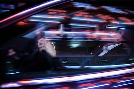 Businessman driving at night, illuminated and reflected lights on the car window Photographie de stock - Premium Libres de Droits, Code: 6116-07236499