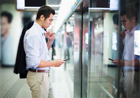 Businessman looking at his phone and waiting for the subway in Beijing Stock Photo - Premium Royalty-Free, Code: 6116-07236587