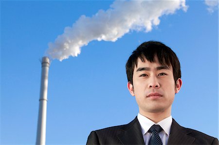 simsearch:6116-07085584,k - Businessman in Front of Smokestack Foto de stock - Royalty Free Premium, Número: 6116-08311884