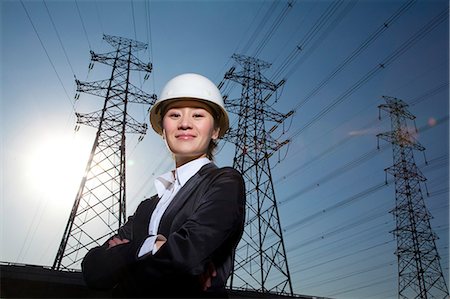 electric tower looking up - Businesswoman in front of power lines Stock Photo - Premium Royalty-Free, Code: 6116-08311889