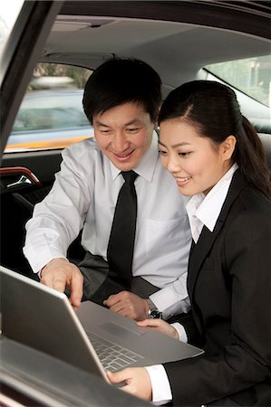 Businesspeople working on laptop in back of car Stock Photo - Premium Royalty-Free, Code: 6116-08312003