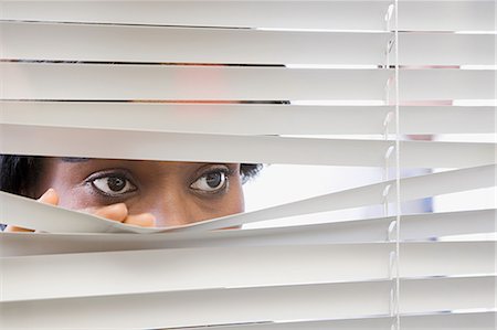 Woman looking through blinds Stock Photo - Premium Royalty-Free, Code: 6116-08915429