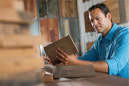 simsearch:6118-07353396,k - A Young Man In A Workshop Examining A Recycled Wood Sample. Photographie de stock - Premium Libres de Droits, Code: 6118-07121798