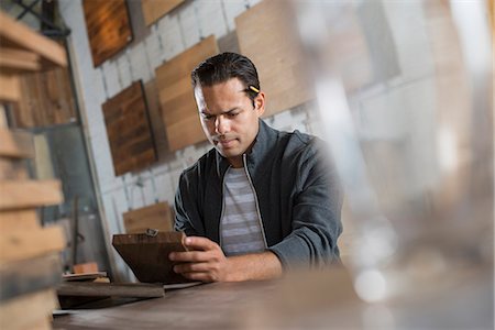 A Young Man In A Workshop Which Uses Recycled And Reclaimed Lumber To Create Furniture And Objects. Stock Photo - Premium Royalty-Free, Code: 6118-07121799