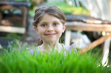 simsearch:6118-07122241,k - On The Farm. A Girl Standing Smiling By A Glasshouse Bench Looking Over The Green Shoots Of Seedlings Growing In Trays. Stock Photo - Premium Royalty-Free, Code: 6118-07121840