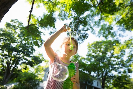 pov - A Young Girl Blowing Bubbles In The Air Under The Branches Of A Large Tree. Stock Photo - Premium Royalty-Free, Code: 6118-07121845