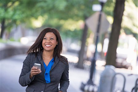 simsearch:6118-07121871,k - Summer. A Woman In A Grey Suit With A Bright Blue Shirt. Holding A Smart Phone. Photographie de stock - Premium Libres de Droits, Code: 6118-07121869