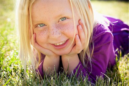 A Young Girl Lying On The Grass On Her Front With Her Chin Resting On Her Hands. Laughing. Close Up. Stockbilder - Premium RF Lizenzfrei, Bildnummer: 6118-07121890