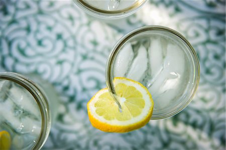 Making Lemonade. Overhead Shot Of Lemonade Glasses With A Fresh Slice Of Lemon In The Edge Of The Glass. Organic Lemonade Drinks. Photographie de stock - Premium Libres de Droits, Code: 6118-07121828