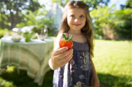 Children And Adults Together. A Young Girl Holding A Large Fresh Organically Produced Strawberry Fruit. Stockbilder - Premium RF Lizenzfrei, Bildnummer: 6118-07121829