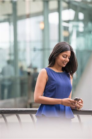 A Woman In A Blue Dress, Checking Her Smart Phone. Foto de stock - Sin royalties Premium, Código: 6118-07121904