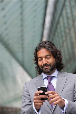 simsearch:6118-07121920,k - Business People. A Man In A Business Suit With A Full Beard And Curly Hair. Using His Phone. Stock Photo - Premium Royalty-Free, Code: 6118-07121916